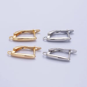 May include: Two pairs of earring findings, one pair is gold and the other is silver. The findings are made of metal and have a curved shape.
