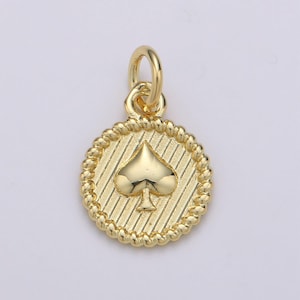 Pode incluir: Encanto de pingente dourado com um símbolo de carta de jogo de paus em um design circular com uma borda de corda.