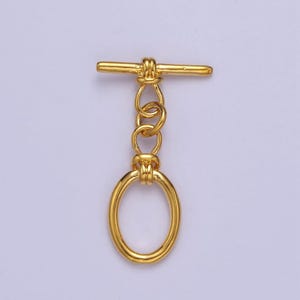 May include: Gold-toned metal toggle clasp with a round ring and a bar. The clasp is designed for attaching to a necklace or bracelet.