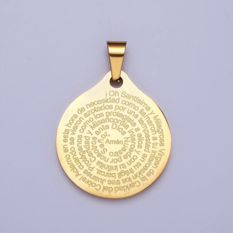 Pu&ograve; includere: Un ciondolo dorato con un ciondolo circolare che presenta un'iscrizione a spirale in spagnolo. L'iscrizione recita: "Oh Sant&iacute;sima y Milagrosa Virgen de la Caridad del Cobre! Aclamo en esta hora de necesidad como azotados por una tempestad vieron los tres Juanes cuando fr&aacute;gil barca. Protegiendolos infinita Caridad y Misericordia intercede por nosotros. Amen."