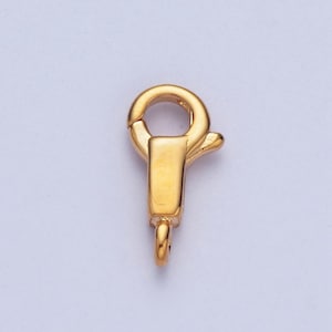 May include: Gold-toned metal clasp with a spring-loaded closure. The clasp has a round loop on one end and a hook on the other end.
