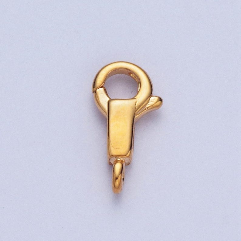 May include: Gold-toned metal clasp with a spring-loaded closure. The clasp has a round loop on one end and a hook on the other end.