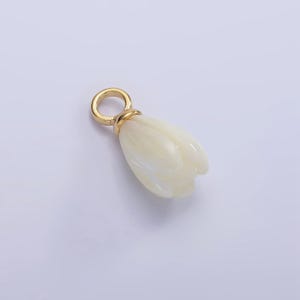 May include: A cream-colored tulip-shaped pendant with a gold-colored loop. The pendant has a carved, petal-like design. The gold loop is attached to the top of the pendant. The background is a solid, light color.
