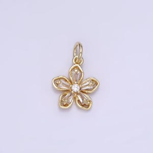 May include: A gold flower charm with clear cubic zirconia stones. The charm has a loop at the top for attaching to a necklace or bracelet.