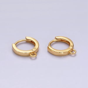May include: A pair of gold-toned hoop earrings with a small jump ring attached to the bottom of each hoop.