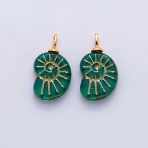 May include: Two green glass pendant charms with a spiral design in gold. Each charm has a gold-colored loop at the top for hanging. The charms are a sea green color and are set against a white background.