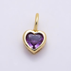 May include: A gold heart-shaped pendant featuring a faceted purple gemstone set in the center. The pendant includes a small gold bail at the top for attachment to a chain, showcasing a polished metallic finish and a deep violet stone.