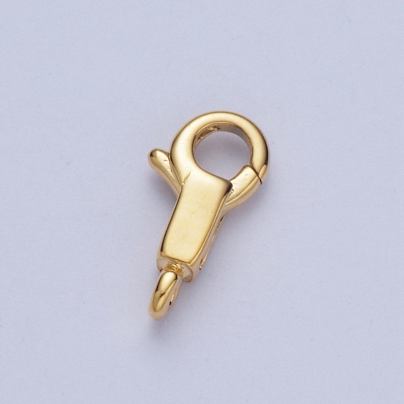 May include: Gold-toned metal clasp with a spring-loaded closure. The clasp is designed for attaching to jewellery chains or necklaces.