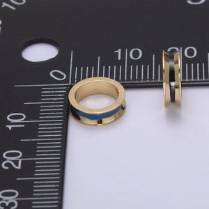 Peut inclure: Deux anneaux dor&eacute;s avec une bande en &eacute;mail bleu et noir. Les anneaux mesurent environ 1 cm de diam&egrave;tre.