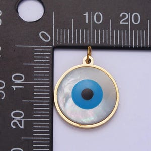 May include: A gold-toned pendant with a white mother-of-pearl background and a blue evil eye design. The pendant is approximately 1 inch in diameter.