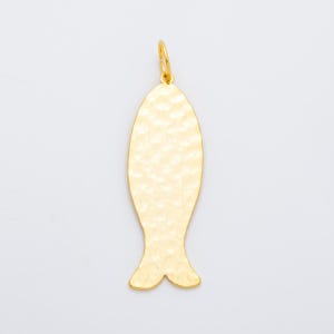 Op de afbeelding: Een goudkleurige visvormige hanger met een getextureerd oppervlak. De hanger heeft een kleine lus aan de bovenkant om op te hangen en een gespleten staartontwerp aan de onderkant. De achtergrond is effen wit.