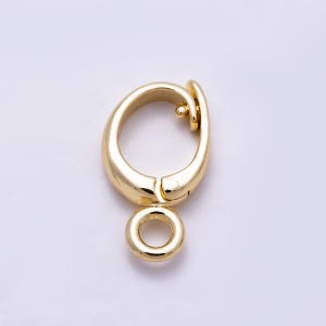 May include: A gold-toned metal lobster claw clasp featuring a smooth, curved teardrop-shaped frame and a small, circular jump ring attached at the base. The clasp mechanism includes a spring-loaded lever for secure opening and closing.