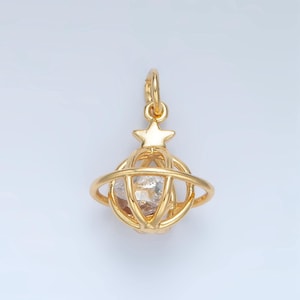 May include: A gold-toned charm featuring a star-topped sphere with a clear crystal inside. The sphere is surrounded by a ring, creating a celestial orb design.