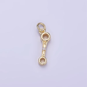 May include: Gold-toned wrench charm with a single clear rhinestone. The charm has a loop at the top for attaching to a necklace or bracelet.