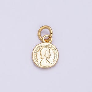 May include: Gold-toned coin charm featuring a profile of a woman's face with an inscription around the edge.