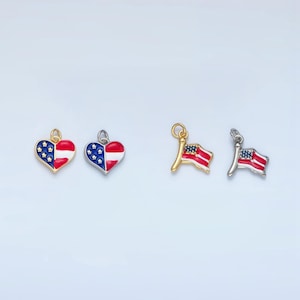 Puede incluir: Cuatro abalorios con la bandera estadounidense en rojo, blanco y azul. Dos abalorios tienen forma de corazón y dos tienen forma de bandera.