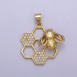 May include: A gold pendant featuring a bee with a yellow gemstone on a honeycomb design with clear gemstones.