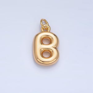 May include: Gold-colored metal charm in the shape of the letter B. The letter is hollow and has a rounded, puffy appearance.