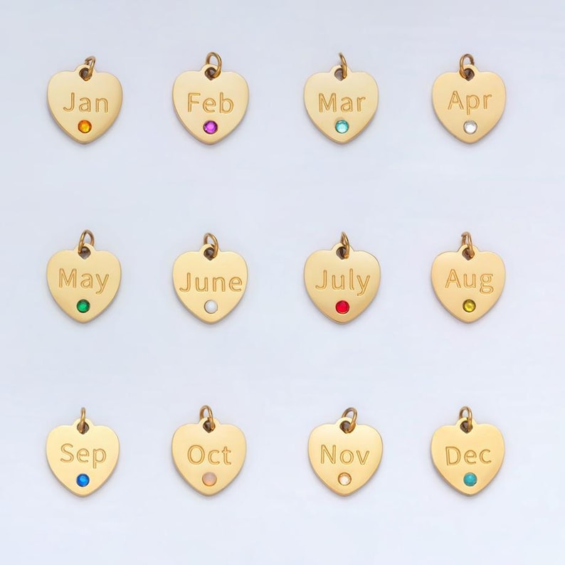 May include: Twelve gold heart-shaped charms with a different month of the year engraved on each charm. Each charm has a small gemstone in the center, representing the birthstone for that month.