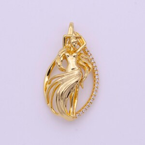 May include: A gold pendant featuring a detailed design of a woman with flowing hair and a skirt, surrounded by a border of clear cubic zirconia stones.