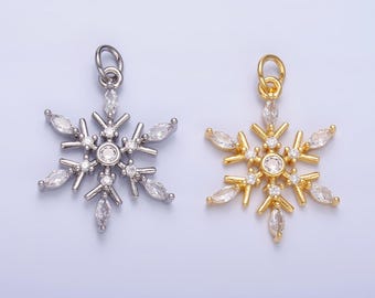 Könnte beinhalten: Zwei Schneeflocken-Anhänger, einer in Silber und einer in Gold, mit klaren Kristall-Akzenten.