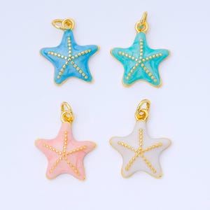 May include: Four starfish charms in shades of blue, teal, pink, and white, each with a gold-colored border and dotted accents. The charms have a loop at the top for attaching to jewelry. These charms are perfect for beach-themed jewelry.