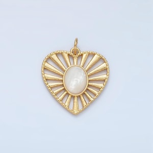 May include: Gold heart-shaped pendant with a white mother-of-pearl inlay in the center. The pendant has a sunburst design with radiating lines.