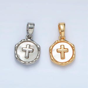 May include: Two silver and gold pendants with a white cross on a white background. The pendants are shaped like a circle with a textured edge.