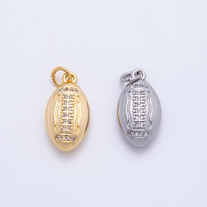 May include: Two football-shaped pendants. One is gold-colored, the other is silver-colored. Both have a detailed design of a football with a loop at the top for a chain. The pendants are likely jewelry charms.