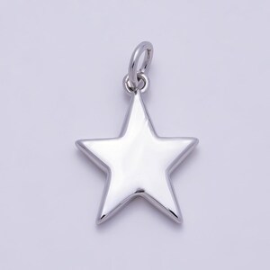 Puede incluir: Un colgante en forma de estrella de color plateado pulido con una superficie lisa y reflectante. La pieza tiene una forma sencilla de cinco puntas e incluye una peque&ntilde;a anilla circular en la parte superior para poder colgarla.