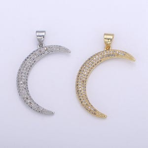 May include: Two crescent moon pendants, one silver and one gold, both with clear crystal accents.