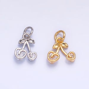 Peut inclure: Deux breloques cerises en argent et or avec des accents de cristal transparent. Les breloques sont en forme de deux cerises avec des tiges et des feuilles.
