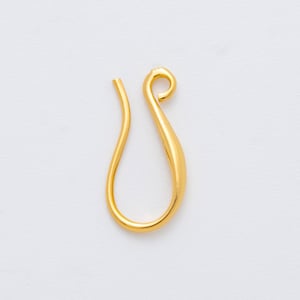 May include: A single, gold-colored earring hook against a white background. The hook has a curved, teardrop shape with a looped top and a straight, open end. The metal has a shiny, reflective surface.