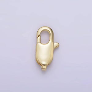 May include: Gold-toned metal clasp with a spring-loaded closure. The clasp is oval-shaped and has a smooth, polished finish.