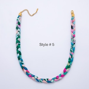 May include: Braided fabric necklace in shades of green, blue, pink, and white, with gold-colored metal clasps and chain. The text "Style #5" is printed on the image. This necklace is a fashion accessory.