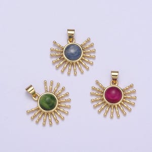以下が含まれることがあります： 中心に異なる色の宝石が埋め込まれた、金色の太陽の形をしたペンダントチャームが3つ。チャームは円形で、太陽の光線が放射状にデザインされています。宝石は青、緑、赤です。