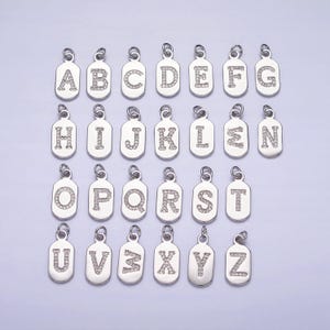 Op de afbeelding: Een set van 26 zilveren bedels, elk met een letter van het alfabet versierd met heldere strass.