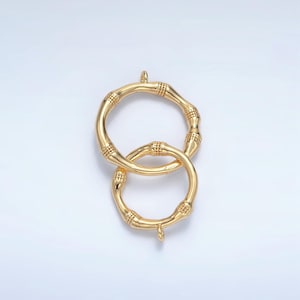 May include: Gold-toned metal connector with a double circle design. The circles are connected and have a textured bamboo-like pattern.