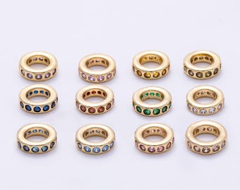 May include: A collection of twelve gold-colored, circular beads. Each bead is adorned with a ring of colorful gemstones, including pink, purple, blue, red, green, and clear stones. The beads are arranged in three rows of four.