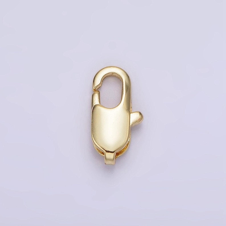 May include: Gold-toned metal clasp with a spring-loaded closure. The clasp is designed for attaching jewelry or other items.
