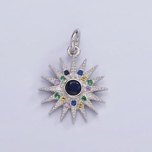 May include: A silver charm in the shape of a starburst with a blue center stone surrounded by smaller colorful stones.