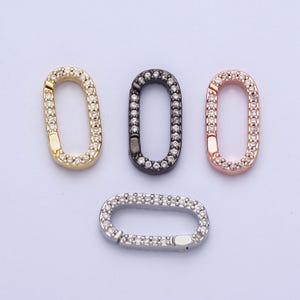 May include: Four oval-shaped connector charms with a clear crystal pave setting. The charms are in gold, black, rose gold, and silver.