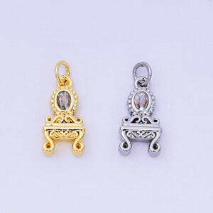 May include: Two decorative pendants, one gold-toned and one silver-toned, each featuring an oval-shaped gemstone. The pendants have a detailed, ornate design with a small loop at the top for hanging. The gold pendant has a warm, shiny finish.