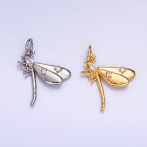 May include: Two dragonfly charms, one silver and one gold, with clear crystal accents. The charms are perfect for jewelry making or adding a touch of whimsy to any project.