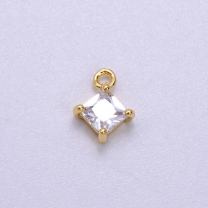 May include: Gold charm with a square clear crystal.