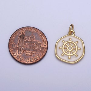 K&ouml;nnte beinhalten: Goldfarbener Anh&auml;nger mit wei&szlig;em Emaille-Steuerraddesign. Der Anh&auml;nger ist sechseckig mit einem goldenen Rand. Eine Ein-Cent-M&uuml;nze liegt neben dem Anh&auml;nger zum Gr&ouml;&szlig;envergleich. Der Anh&auml;nger hat eine kleine Schlaufe f&uuml;r eine Kette.