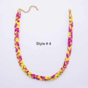 May include: A braided necklace featuring alternating strands of yellow and magenta fabric. The necklace has a gold-colored chain and clasp. The text "Style # 4" is printed on the white background.