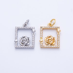 May include: Two square pendants, one silver-toned and one gold-toned, each featuring a rose within a square frame. The frames are encrusted with small, clear stones. Star-shaped accents are on the corners of the frames. The pendants are for jewelry.
