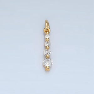 May include: A gold pendant with a row of five clear round stones.
