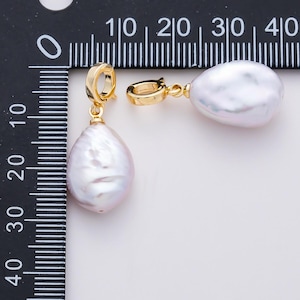 May include: A pair of gold-colored drop earrings featuring large, irregularly shaped, white pearls. The earrings have a gold-colored clasp. The pearls are approximately 1.5 inches in length.